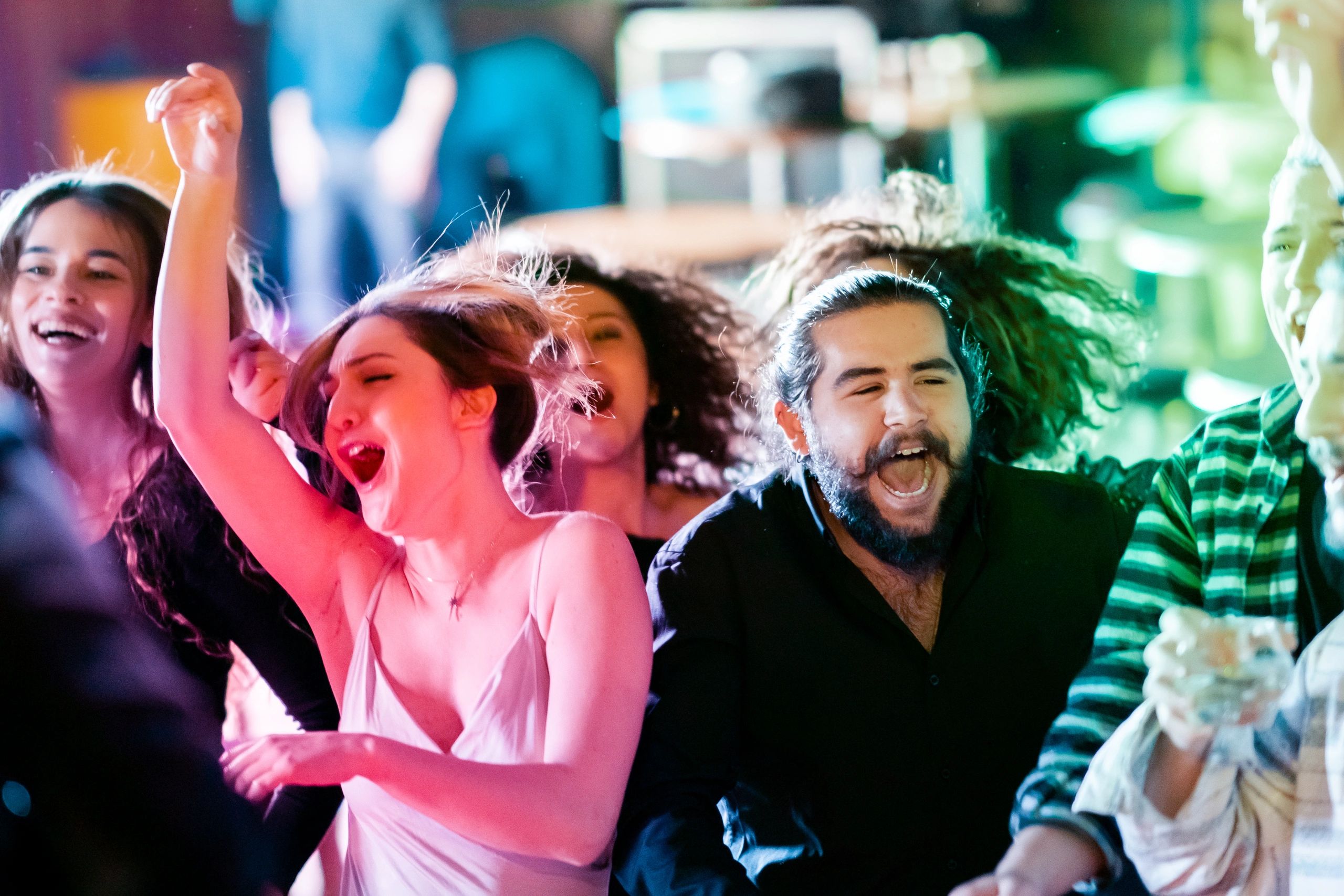 Crowd dancing at DJ event with vibrant lighting